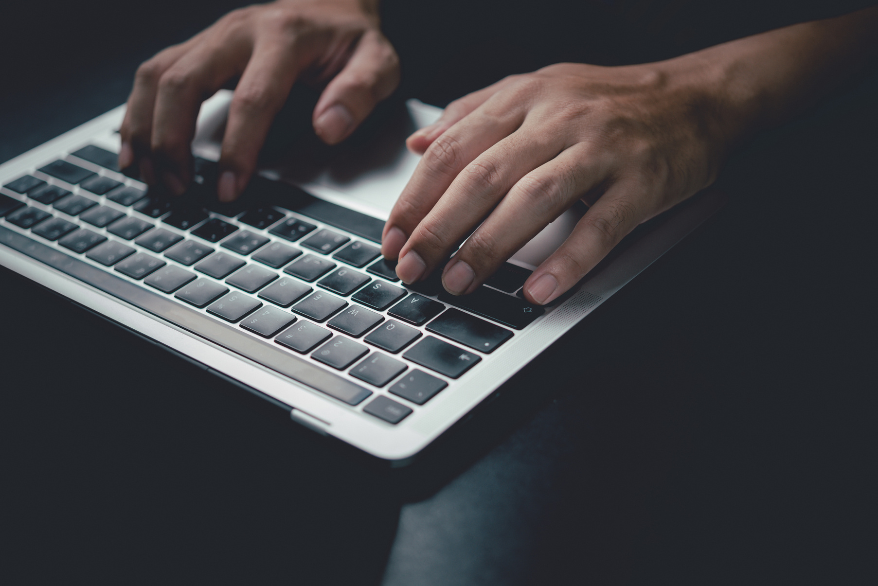 Man using computer laptop working internet searching social media and communications digital technology online at desk.